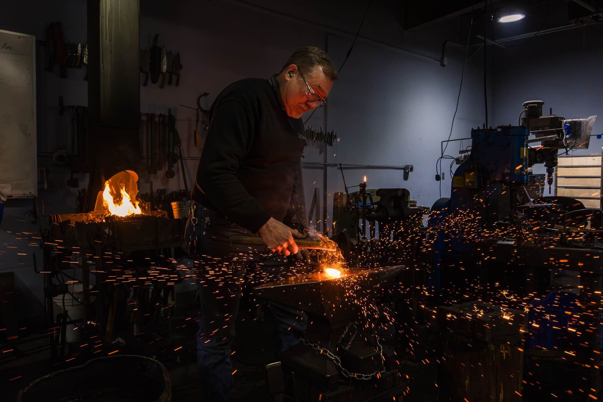 A smith at the anvil in the VIB shop, sparks flying off the hot iron