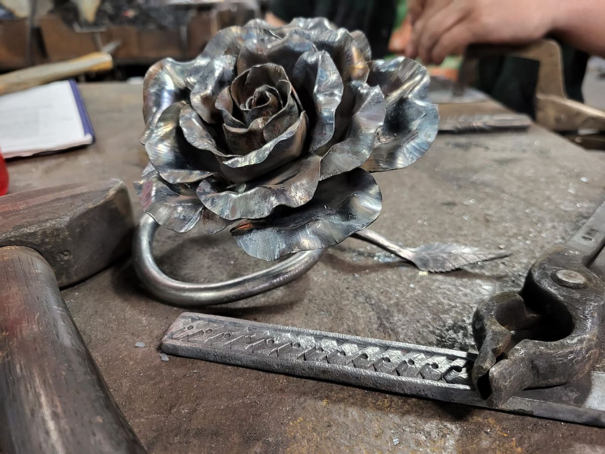 A forged steel rose resting on an anvil